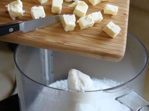Butter cubes being added to food processor.