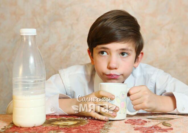 Сомневающийся мальчик пьет молоко, фото