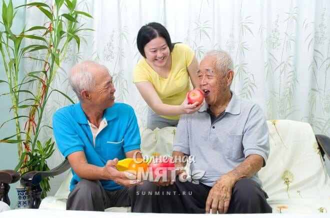 Внучка-китаянка угощает своего дедушку яблоком, фото